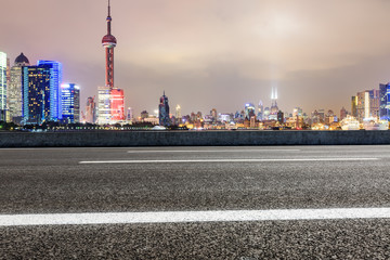 Asphalt road and modern cityscape at night in Shanghai