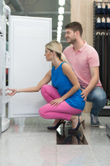 Smiling Couple Buying A Fridge In Supermarket