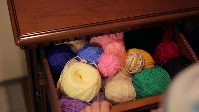 Beautiful woman gets out of the chest a skein of thread.