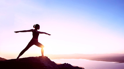 Fototapeta premium Silhouette woman with yoga posture on the mountain at sunset.