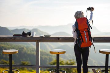 The woman takes photos of sunrise by compact camera  in sunshine