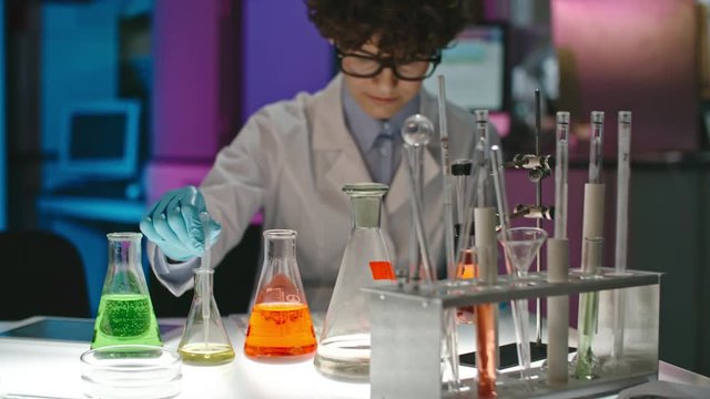 Female scientist in glasses working with colorful solutions in laboratory 
