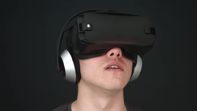 Laughing young man wearing VR Headset experiencing virtual reality. Captured with Blackmagic Production Camera 4K with RAW settings.