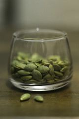 Pumpkin seeds in the glass bowl over wooden background close up