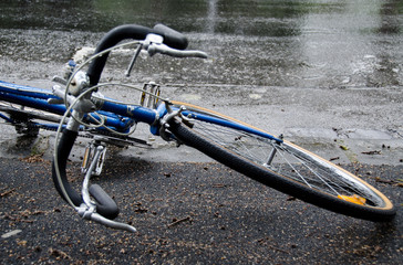 Bicycle fallen over on road in the rain