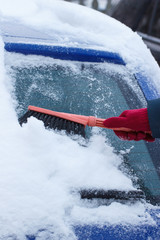 Hand of woman using brush and remove snow from car and windscreen