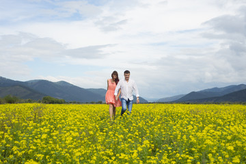 Lovers man and woman walk on the flower field.