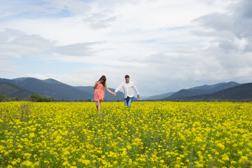 Lovers man and woman walk on the flower field.