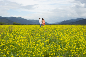 Lovers man and woman walk on the flower field.