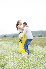 Lovers man and woman walk on the flower field.