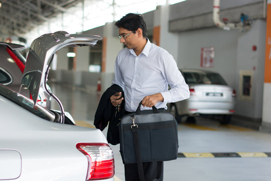 Full Length Of Businessman Unloading Luggage From Car Boot At Ai