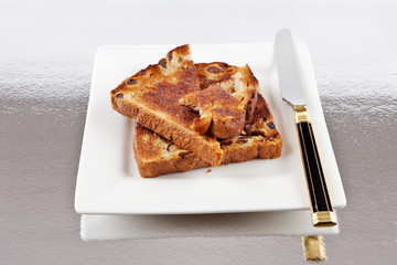 Raisin toast on a plate with butter anda knife