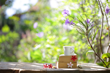 Books with flowers and cup on wooden table