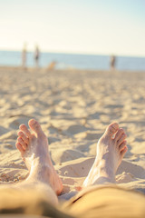 Feet closeup on beach on sunbed enjoying sun on sunny summer day.