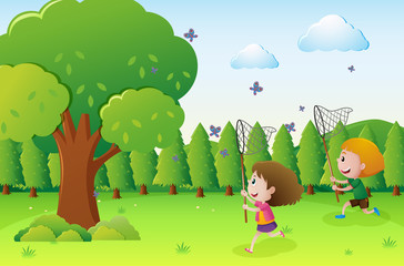 Obraz na płótnie Canvas Park scene with two kids catching butterflies