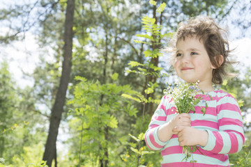 Spring in the forest little girl holding a small bouquet lily of