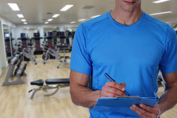 Personal fitness trainer with workout plan close up in gym background. Sport, fitness and healthy life style concept.