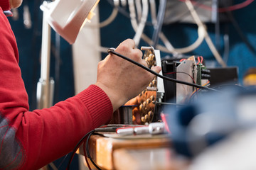 Man with safety glasses repairing motheboard with soldering iron