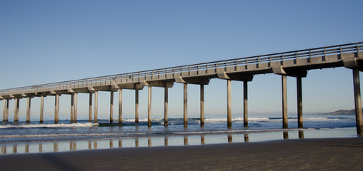 Naklejka premium Reflections in sunrise under a tall Pier at La Jolla Bay