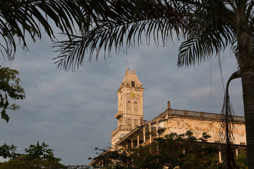 Beit-al-Ajaib (House of wonders) in Zanzibar Stone town. Lit up with sunlight and framed with foliage.