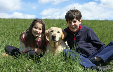 brother and sister with their labrador dog on the grass
