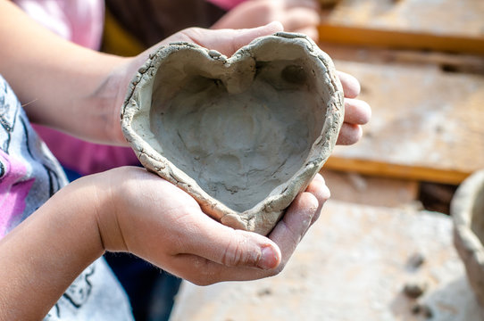 The child shows heart made with his own hands from white clay