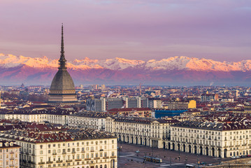 Torino (Turin, Italy): cityscape at sunrise with details of the Mole Antonelliana towering over the city. Scenic colorful light on the snowcapped Alps in the background. - obrazy, fototapety, plakaty