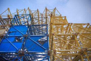 A pile of scrap metal in the snow. Several old building cranes.