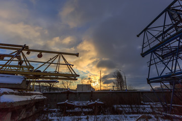 A pile of scrap metal in the snow. Several old building cranes o