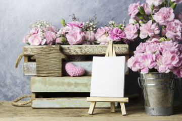 Pink carnation flowers and blank canvas frame on easel painting