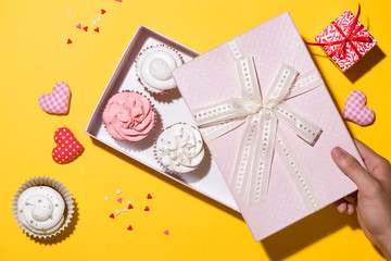 Delicious cupcake with paper box on yellow background