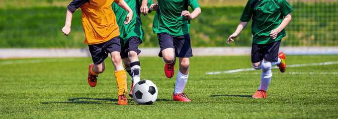Running Youth Football Players. Kids Playing Football Soccer Game on Sports Field. Boys Play Soccer Match on Green Grass. Youth Soccer Tournament Teams Competition. 