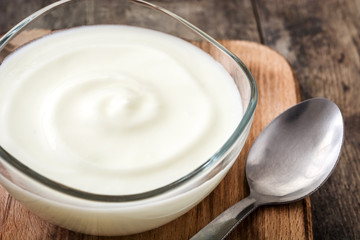 Greek yogurt in glass bowl on wooden table
