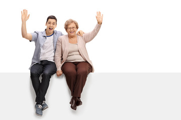 Young man and elderly woman sitting on panel and waving