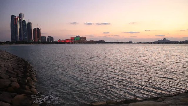 Abu Dhabi skyline at sunset with skyscrapers lit up for the 43rd National day