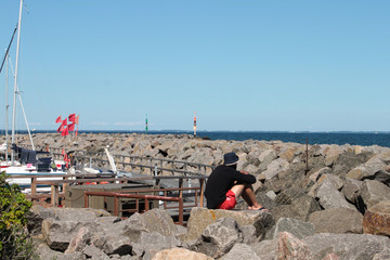 Ein Tourist sitzt am Hafen in Löhne, Insel Rügen 