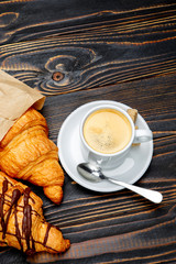 cup of coffe and croissant on wooden background