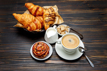 cup of coffe and cinnabon on wooden background