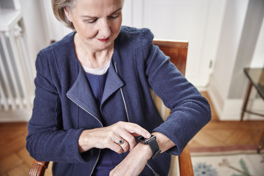 Senior woman sitting on chair looking at smartwatch