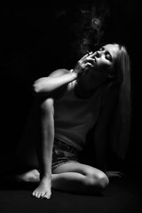 young woman sitting in dark smoking cigarette monochrome