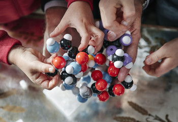 Hands of grandfather and grandchildren assembling molecular model