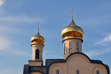 Orthodox Church St. Seraphim of Sarov in the village Obukhovo, Grodno region, Belarus. Front facade with gold domes against the blue sky.