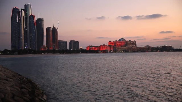 Abu Dhabi skyline at sunset with skyscrapers lit up for the 43rd National day