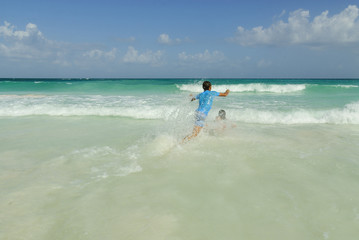 Fototapeta na wymiar children playing in the water in the paradisiac Xpu-ha beach in the Mexican Caribbean sea.