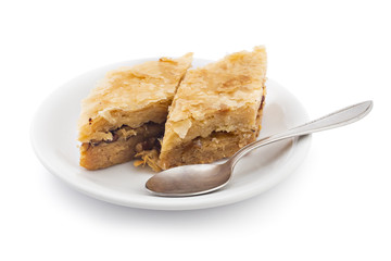 Turkish cake baklava pieces, traditional sweet, on white plate with spoon isolated on white background