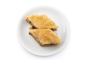 Turkish cake baklava pieces, traditional sweet, on white plate isolated on white background
