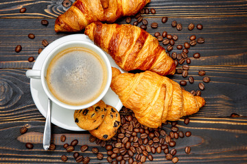 cup of coffe and croissant on wooden background