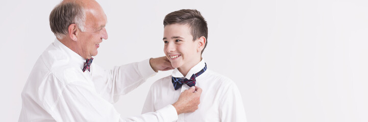 Grandfather dressing grandson in a bow tie