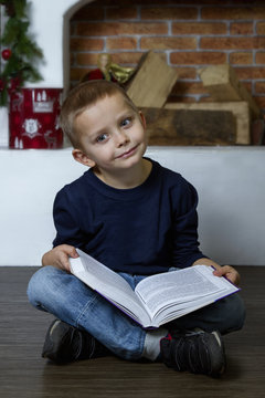 Cute little boy reading a book.