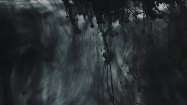 Black paint on the white background doing stains because of drop into water.